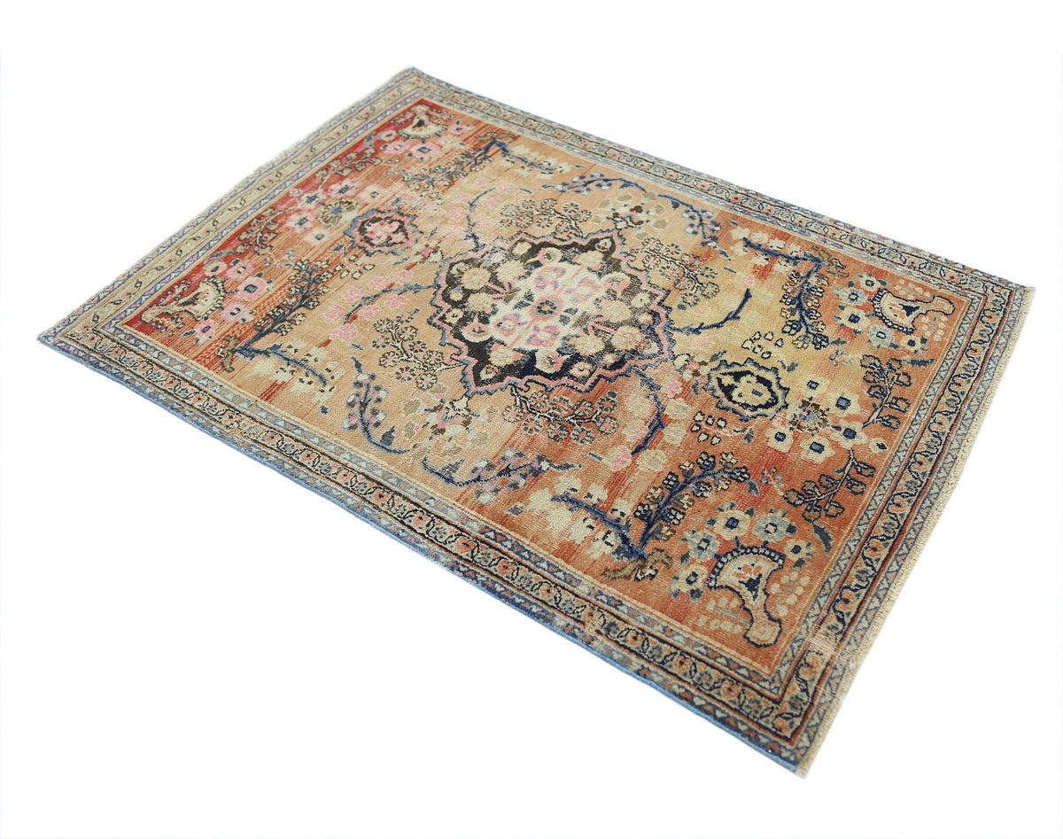 A vintage handmade Persian rug featuring a central floral medallion on an orange field.