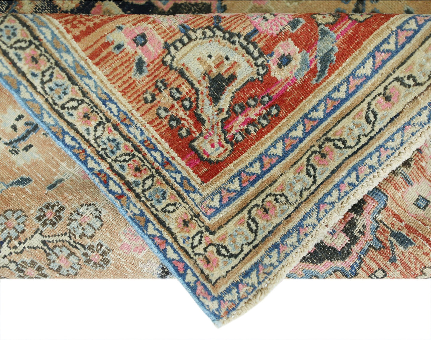 A folded vintage Persian rug featuring intricate floral patterns in red, blue, and beige tones.