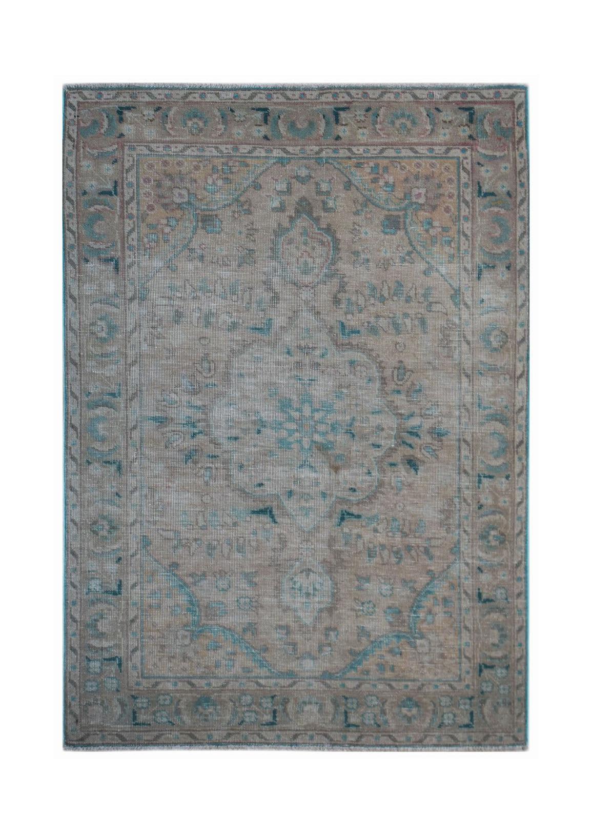 A vintage handwoven Persian rug featuring a faded floral medallion in muted blue and beige tones.