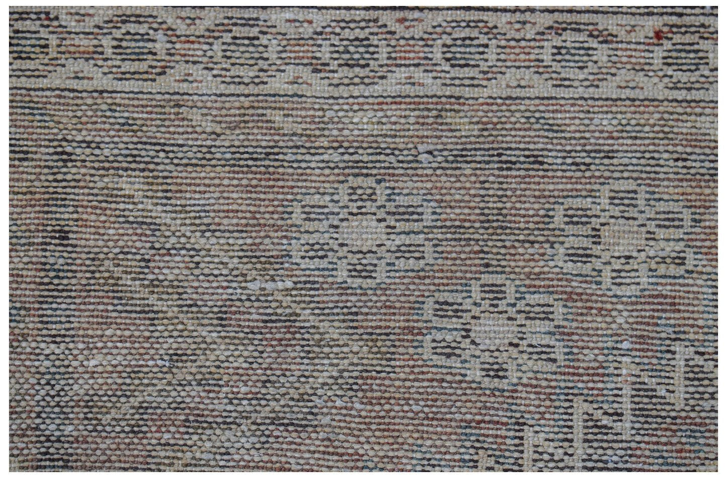 A close-up of a vintage handwoven Persian rug featuring a faded floral pattern and border.