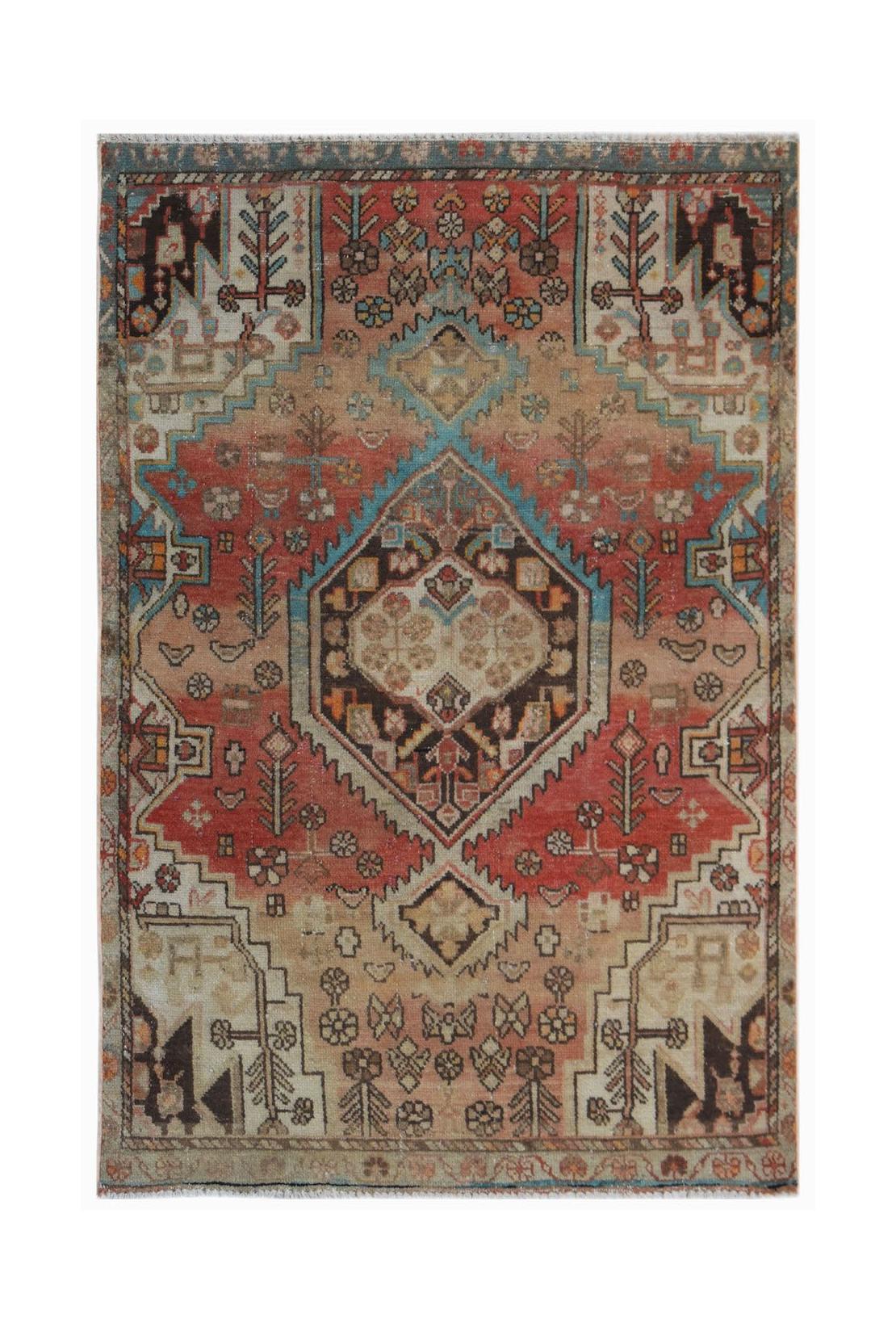 A handwoven vintage Persian rug featuring a central geometric medallion in red, blue, and beige.