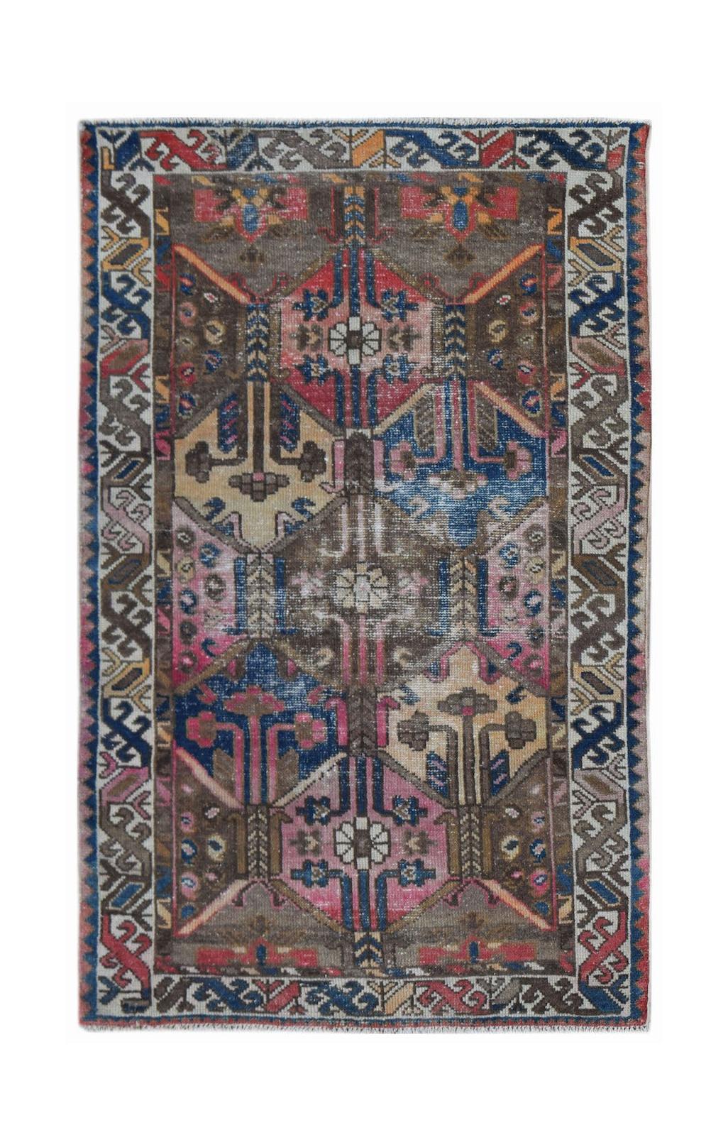 A vintage handwoven Persian rug featuring a geometric pattern in shades of brown, pink, and blue.
