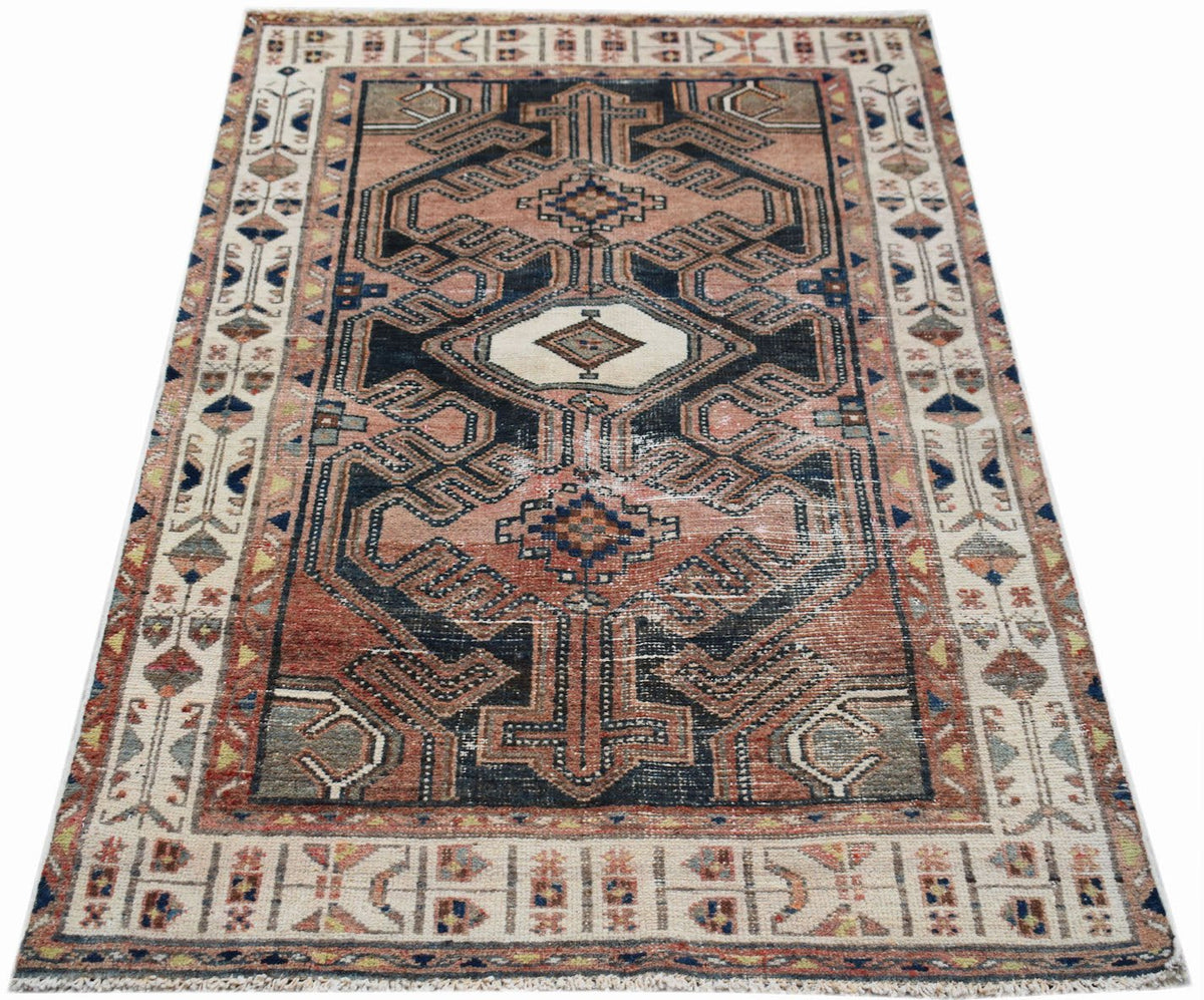 A vintage handwoven Persian rug featuring a geometric pattern in muted red, blue, and cream tones.