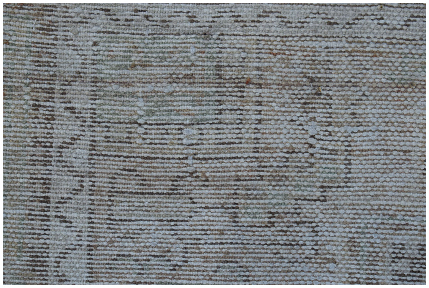 A close-up view of a handwoven vintage Persian rug featuring a faded, distressed geometric pattern.