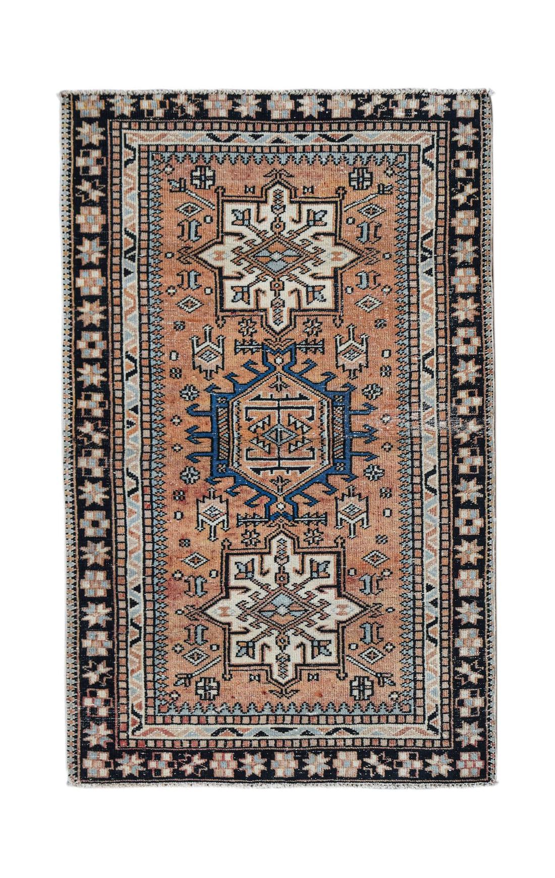 A handwoven vintage Persian rug featuring geometric patterns in orange, blue, and cream tones.
