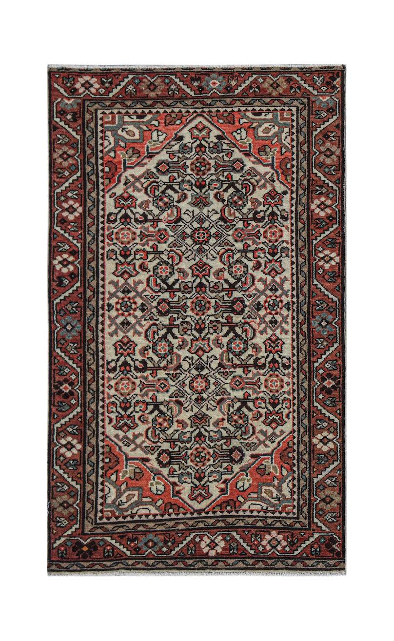 A handwoven vintage Persian rug featuring a central floral medallion on a cream and red field.