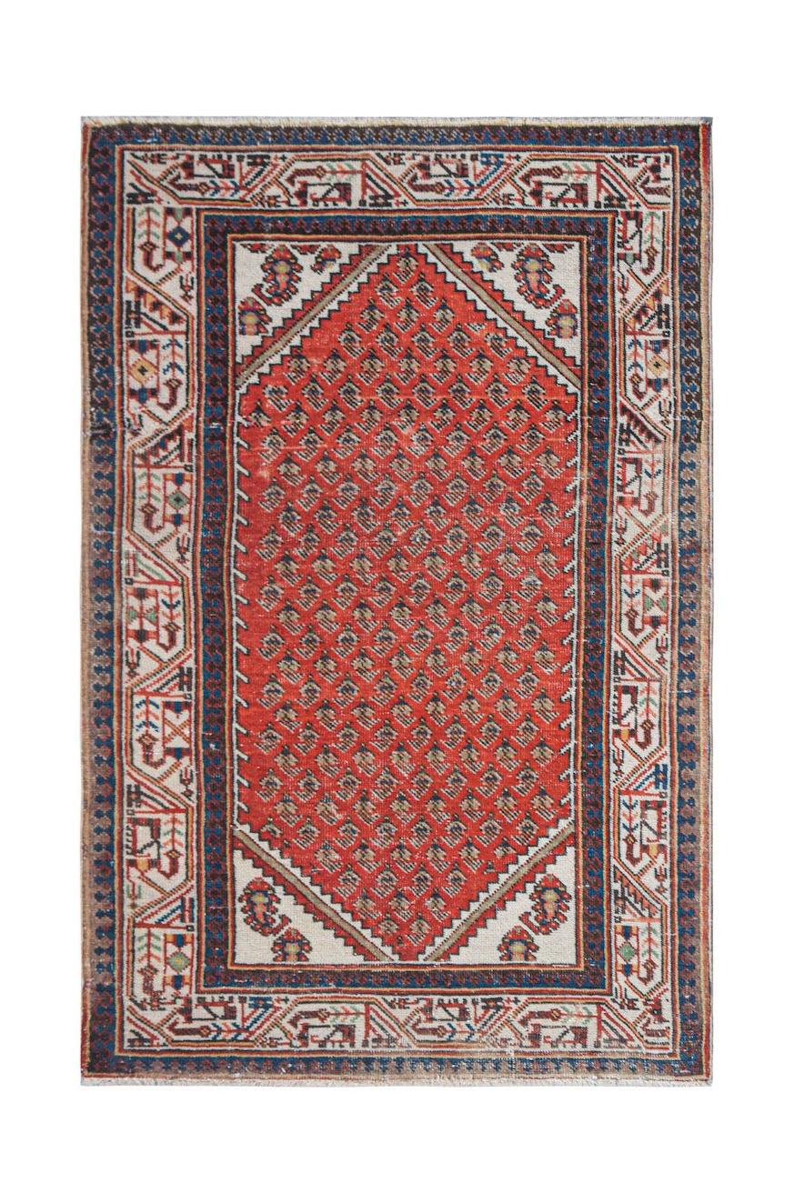 A handwoven vintage Persian rug featuring a red central field with geometric patterns.