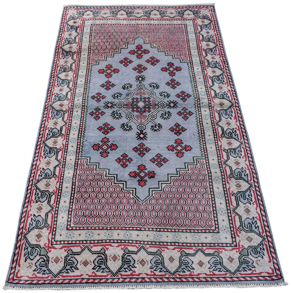 A handwoven vintage Persian rug featuring a light blue central medallion with red geometric motifs.