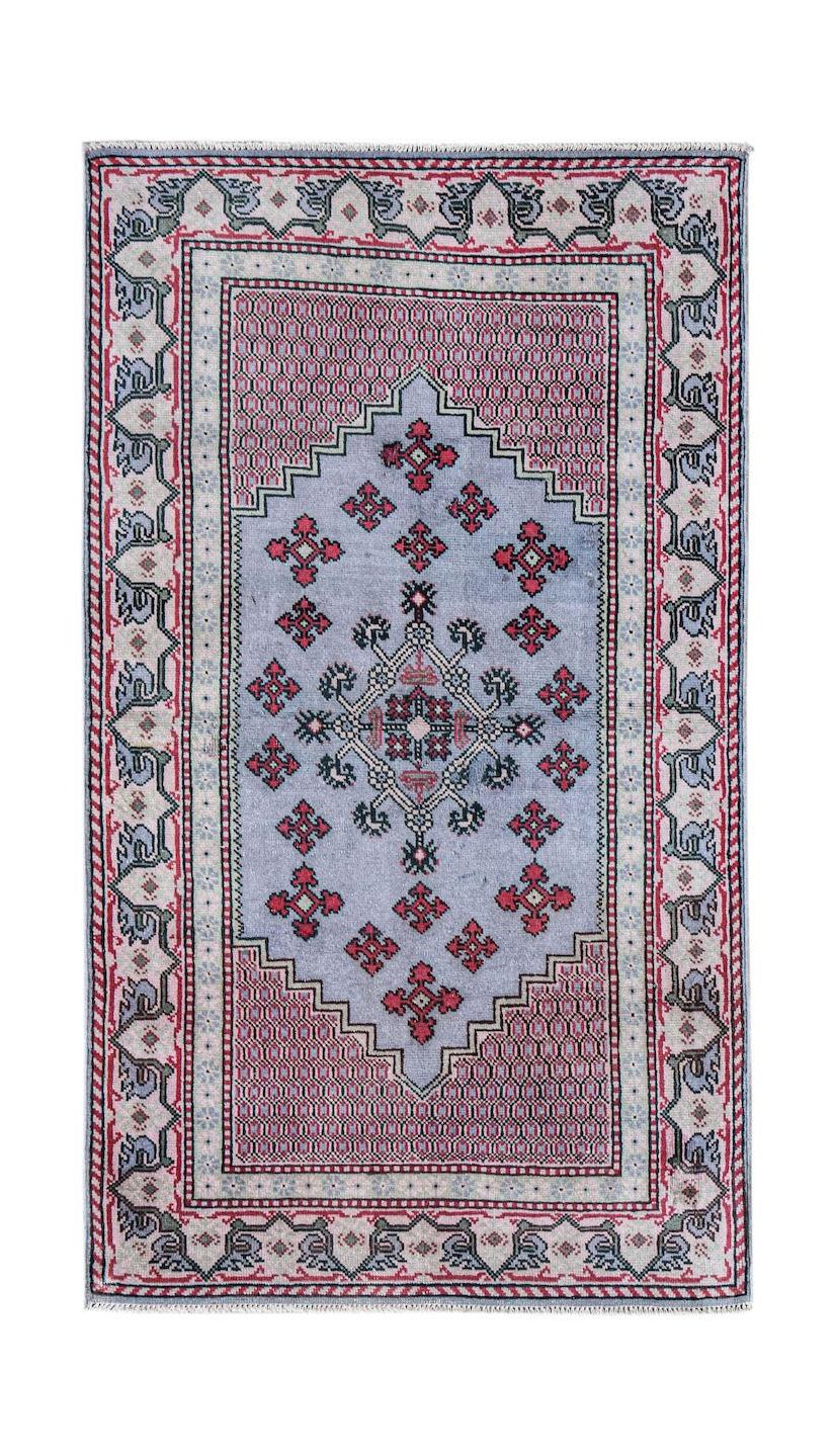 A handwoven vintage Persian rug featuring a blue central medallion with red geometric motifs.