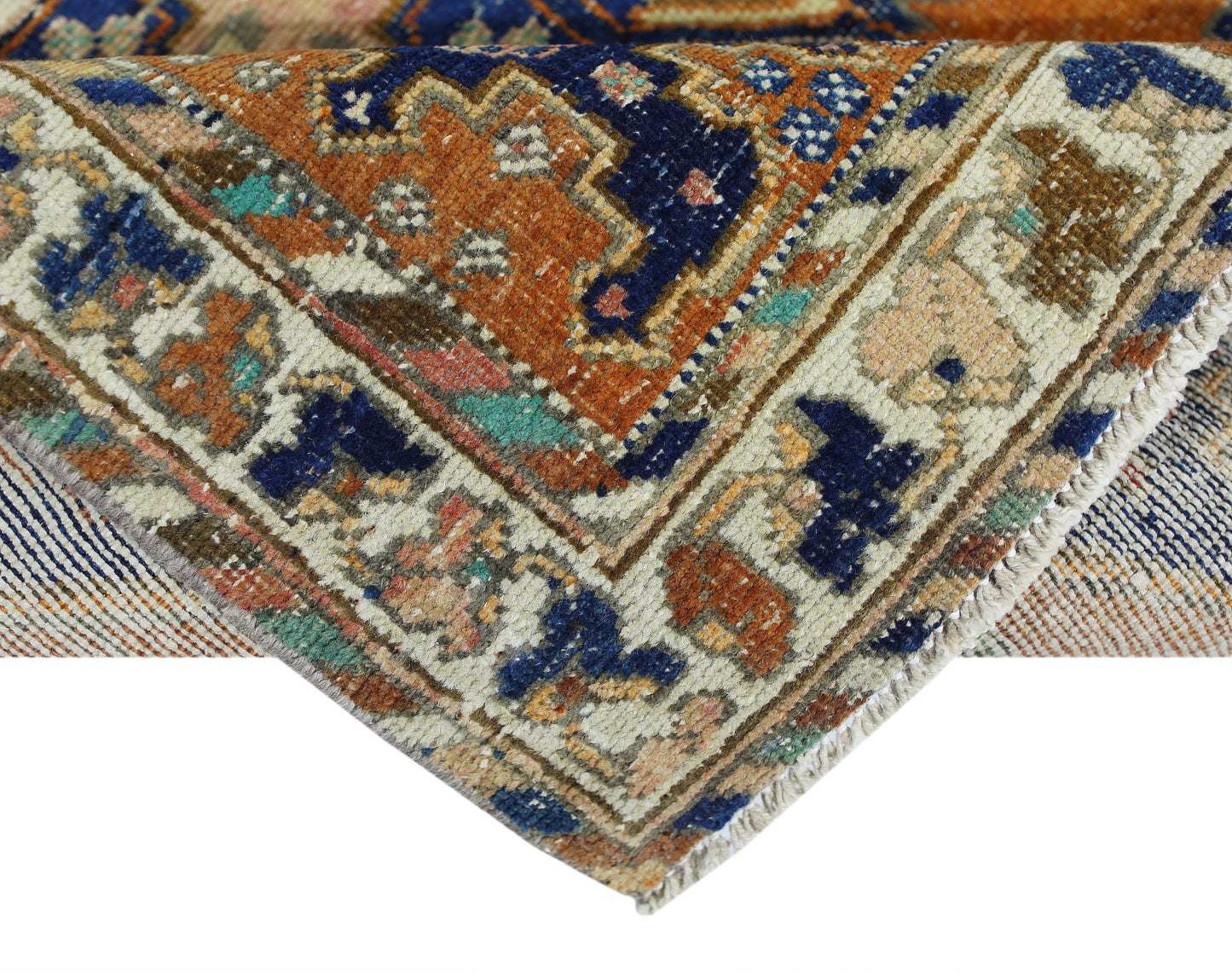 A corner view of a vintage Persian rug featuring intricate geometric patterns in blue and orange.