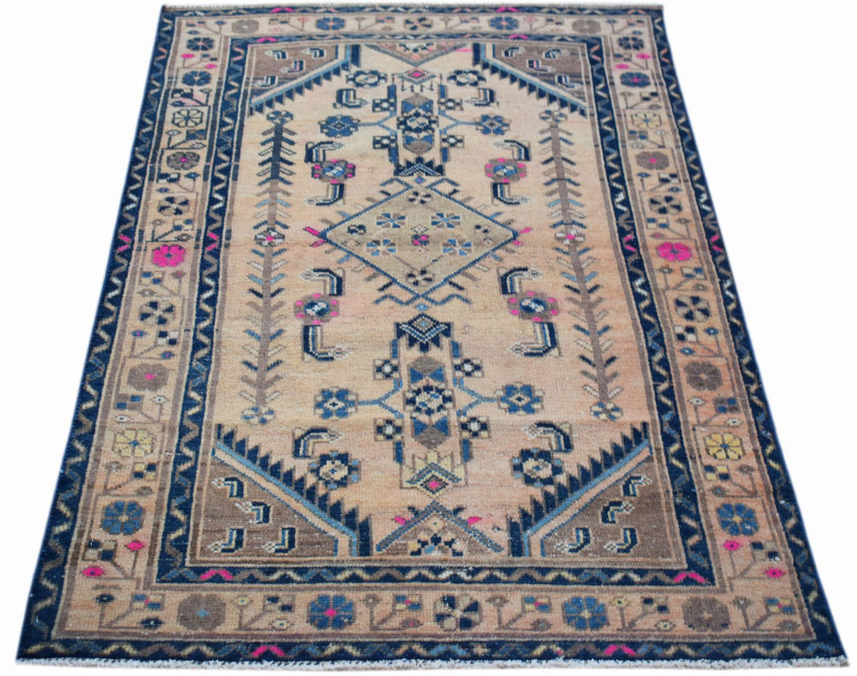 A handwoven vintage Persian rug featuring a geometric pattern in blue, pink, and tan tones.