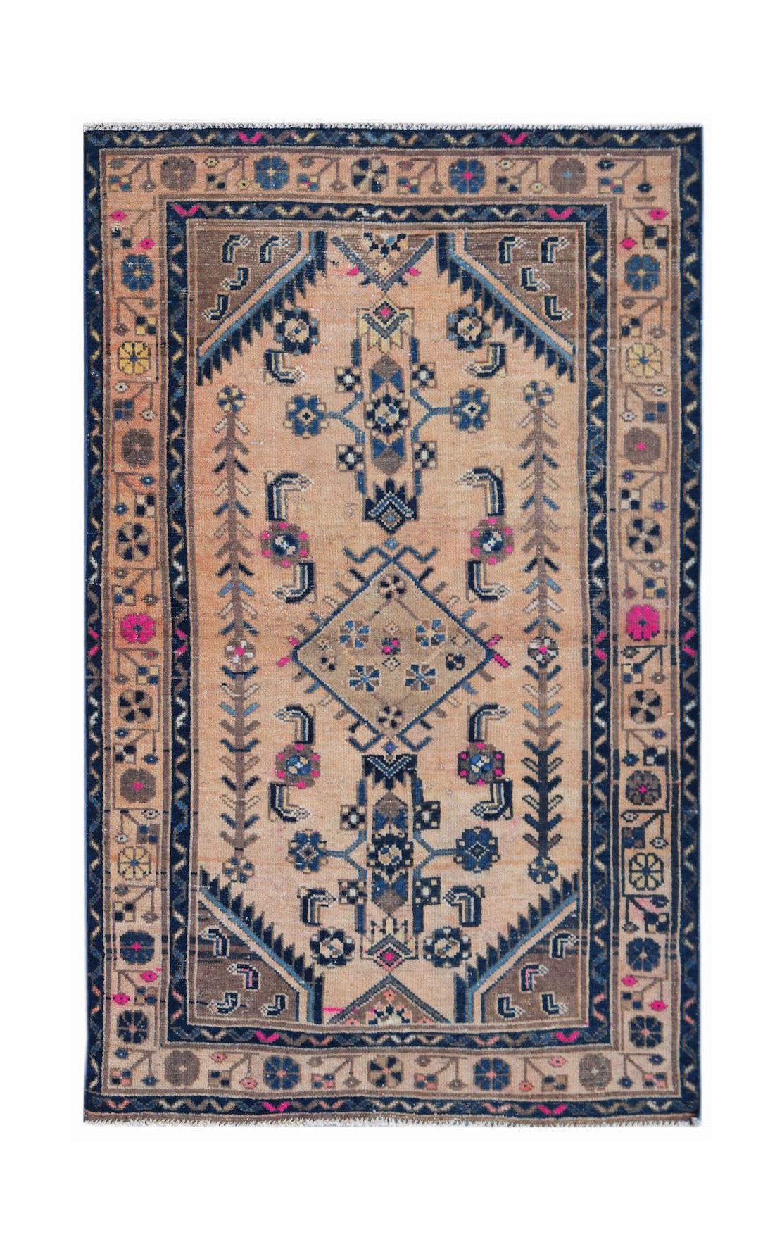 A handwoven vintage Persian rug featuring a geometric pattern in blue, pink, and tan wool.