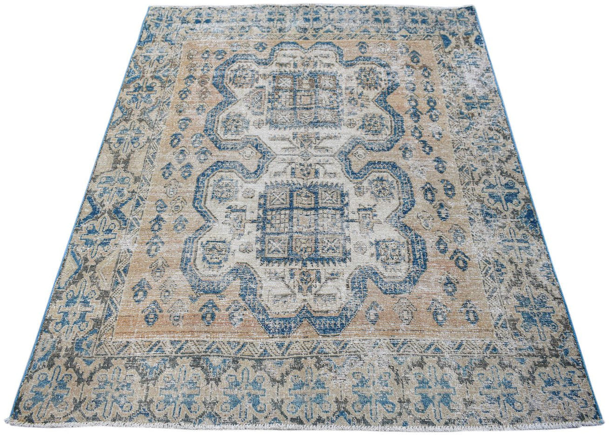 A vintage handwoven Persian rug featuring a distressed blue and tan geometric medallion pattern.