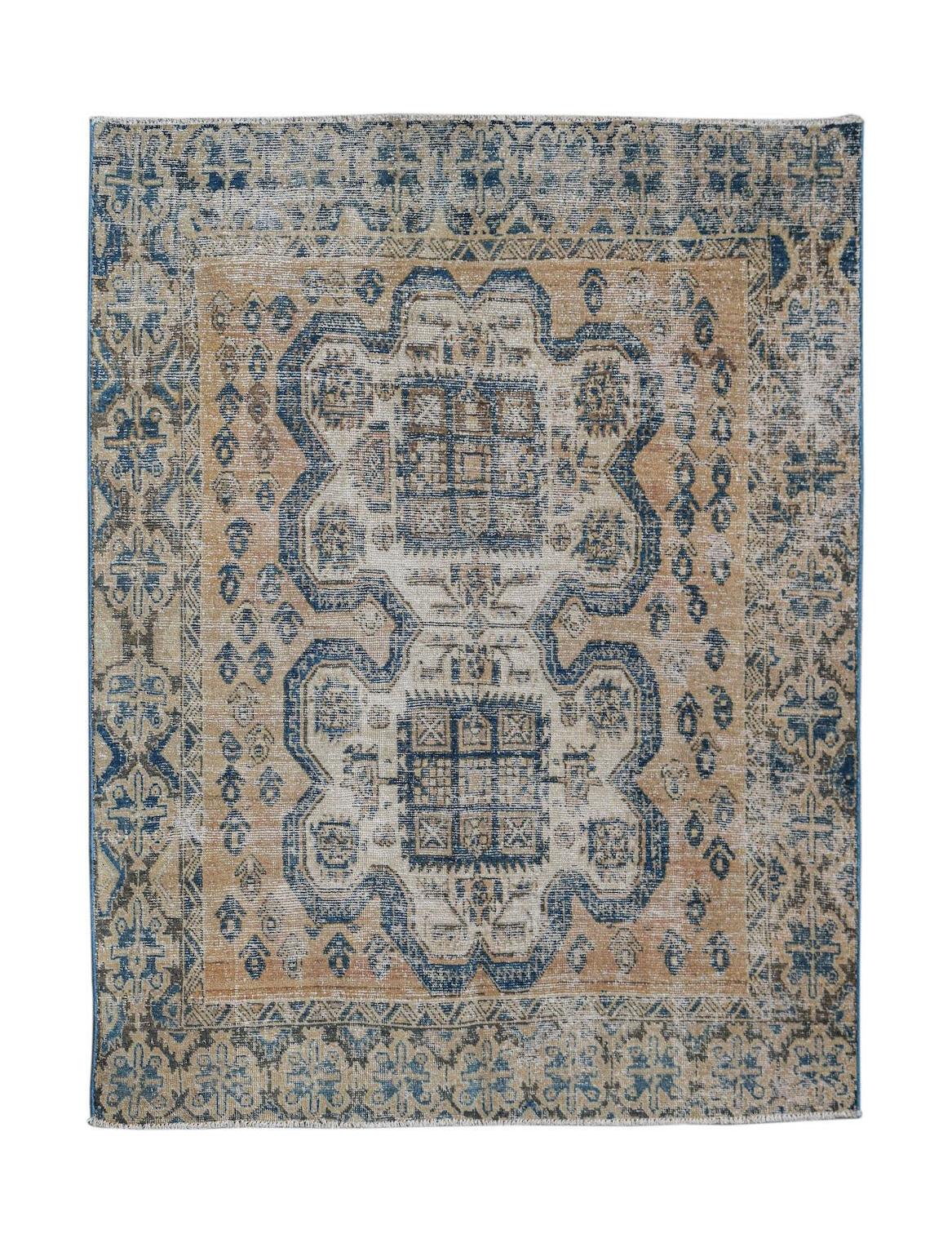 A vintage handwoven Persian rug featuring a blue and tan geometric medallion pattern.