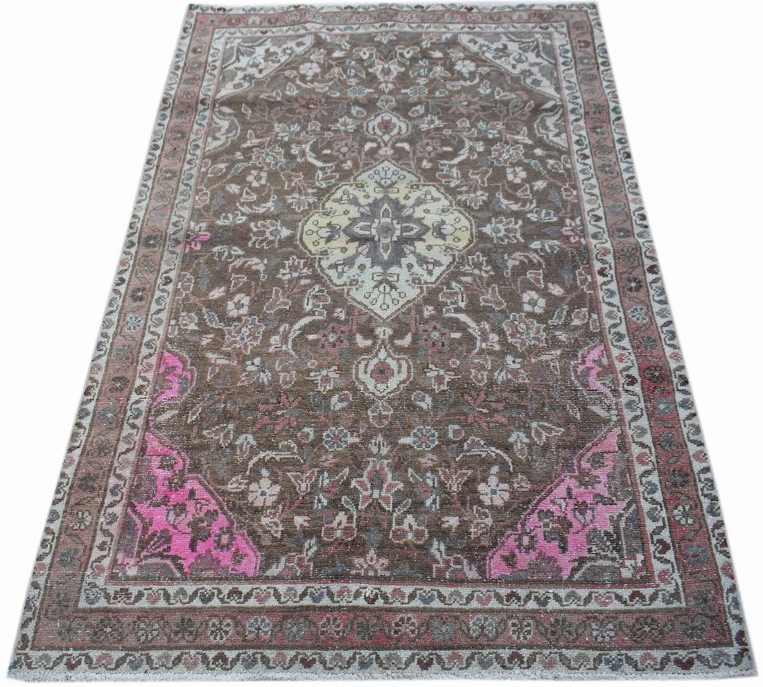 A vintage handwoven Persian rug featuring a brown field with pink accents and a central medallion.