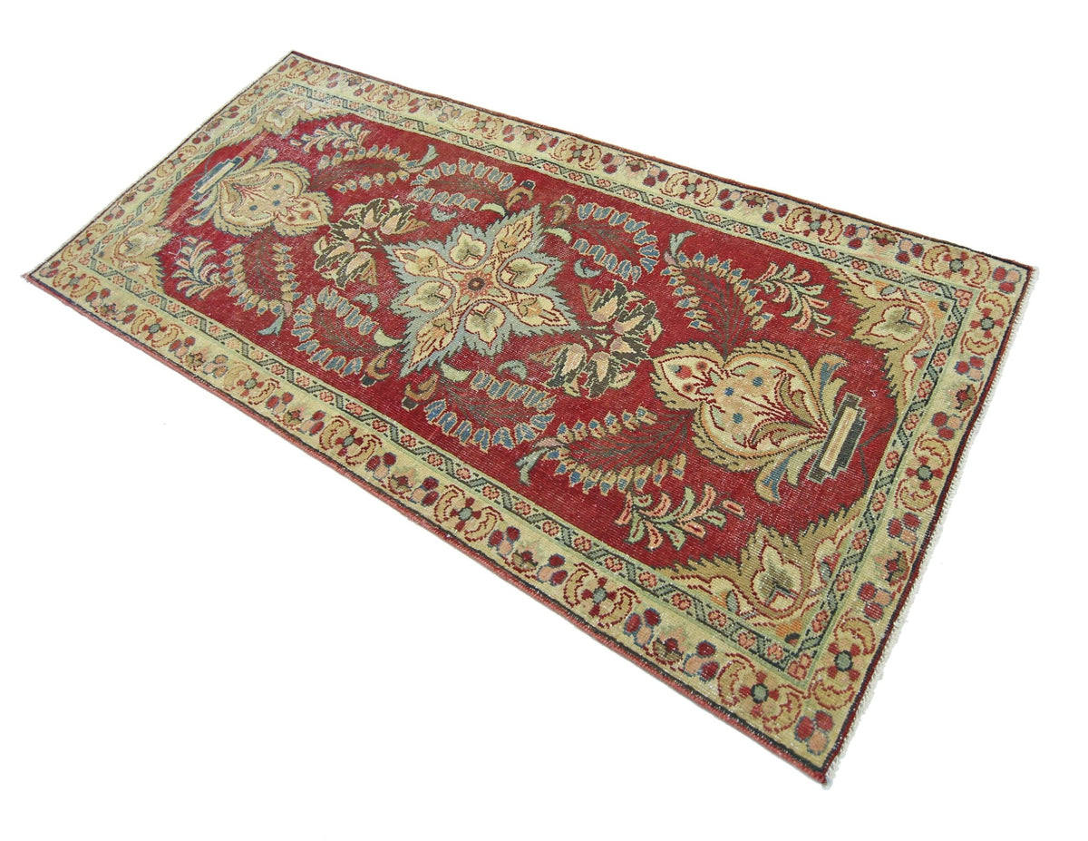 A rectangular vintage Persian rug featuring a floral pattern in red, beige, and blue tones.