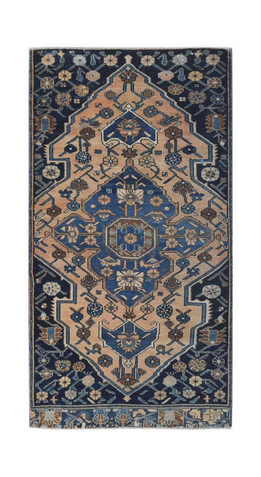 A handwoven vintage Persian rug featuring a geometric floral medallion in blue and tan tones.
