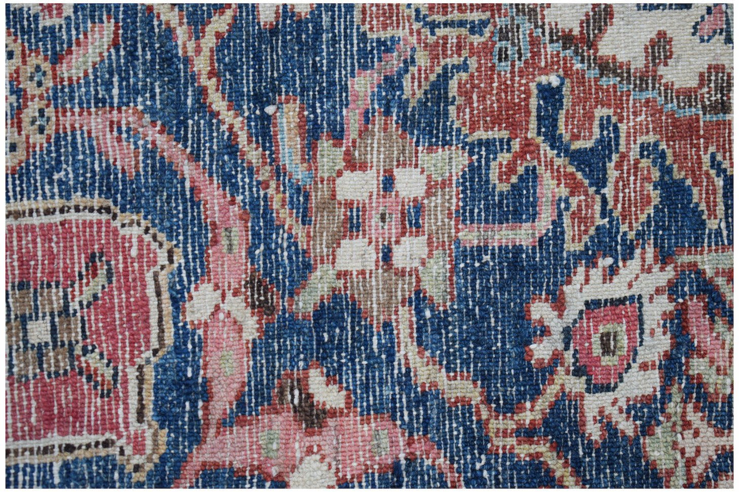 A close-up view of a vintage Persian rug featuring intricate floral patterns in blue, red, and cream.