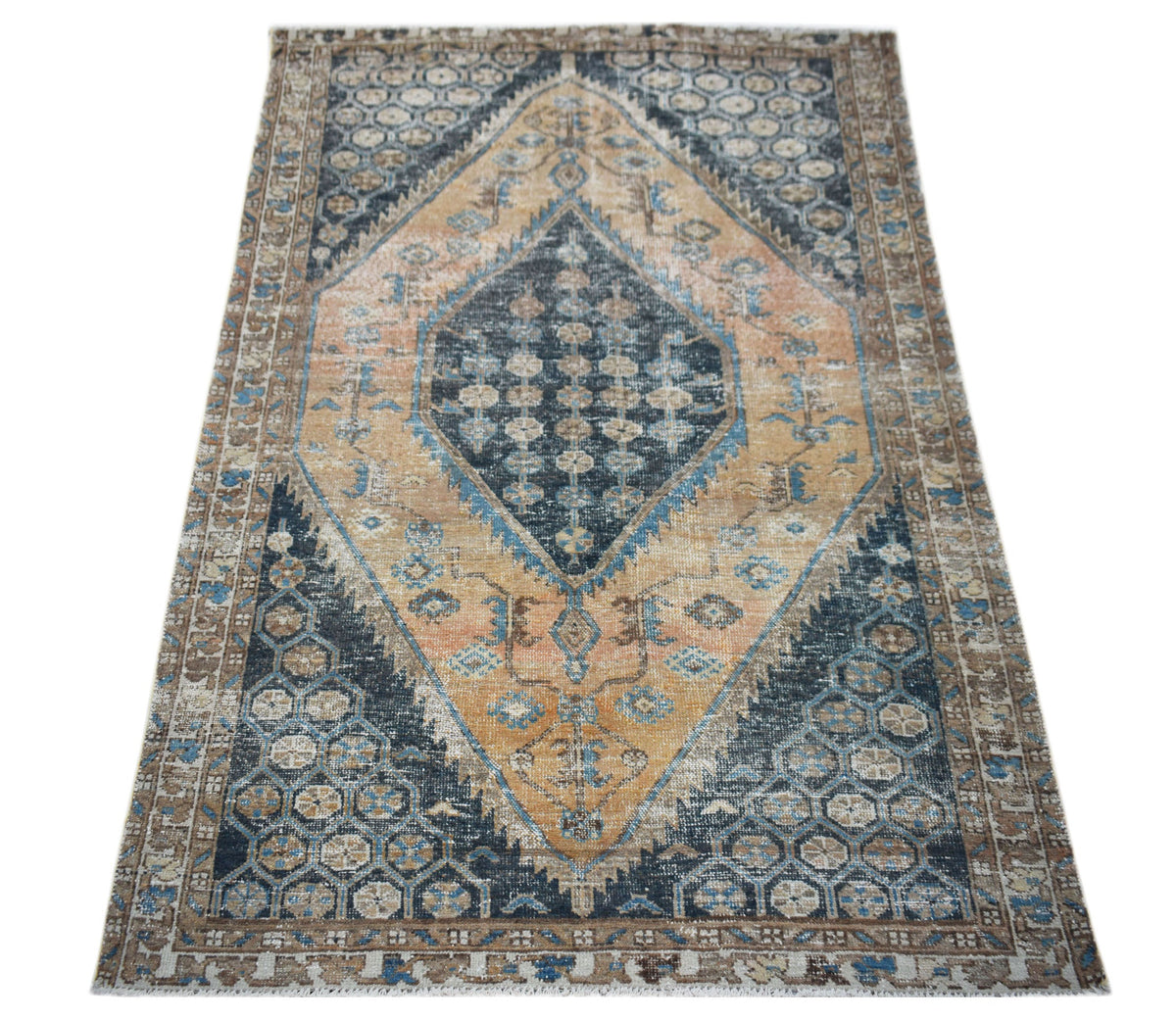 A vintage handwoven Persian rug featuring a central diamond medallion in blue and tan tones.