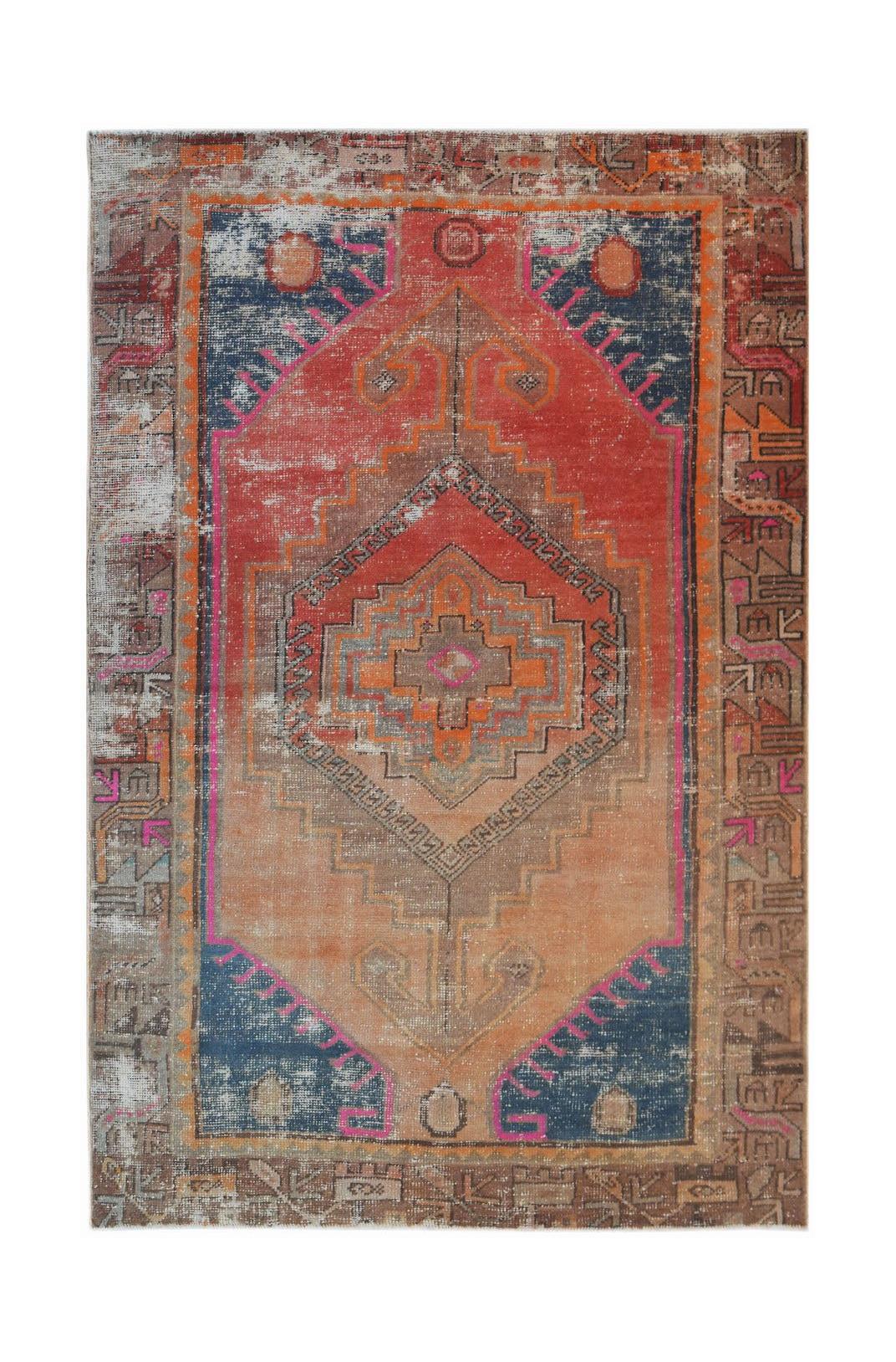 A handwoven vintage Persian rug featuring a geometric medallion in shades of red, blue, and orange.
