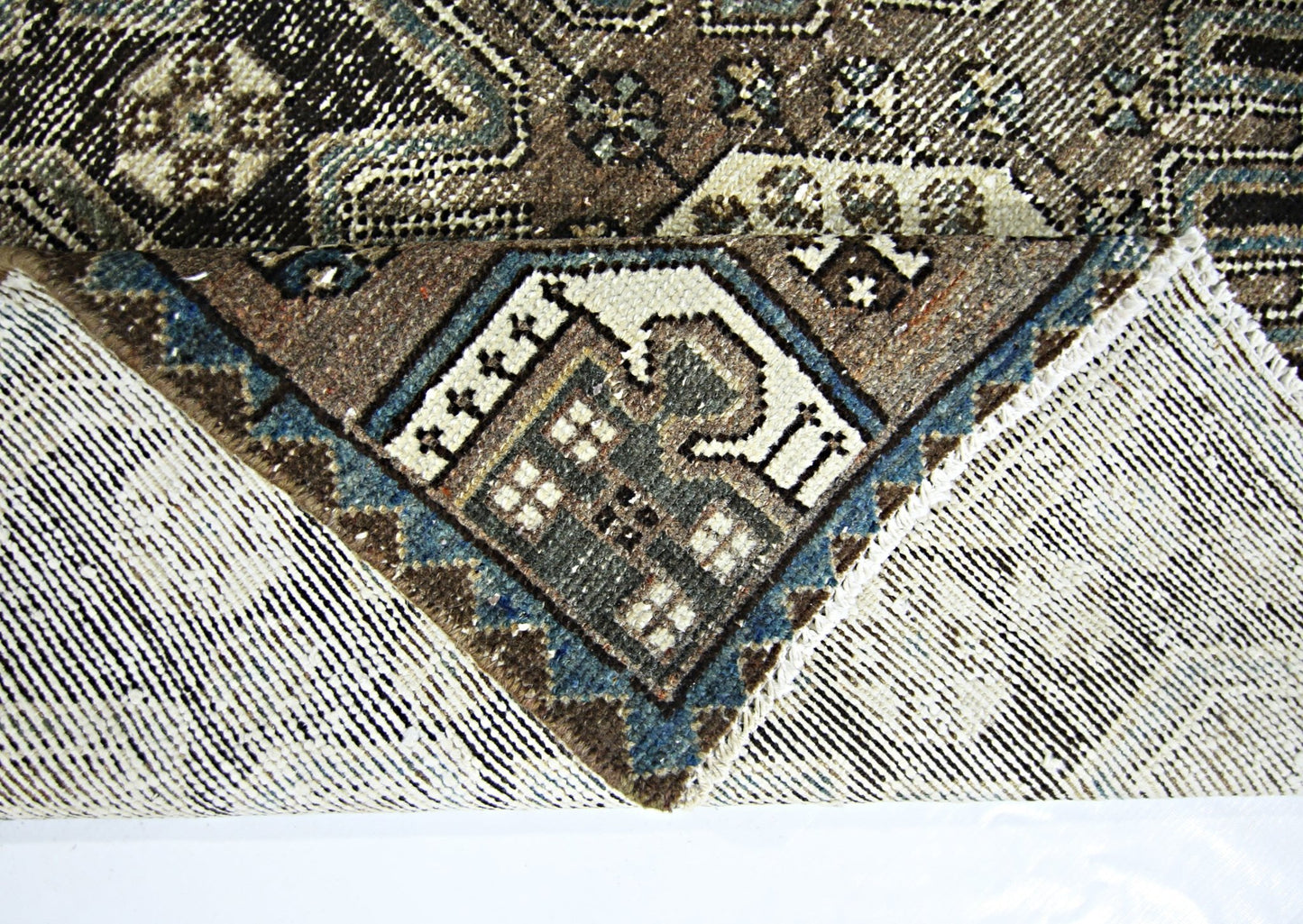 A vintage handmade Persian rug with a geometric pattern in brown, blue, and cream wool.
