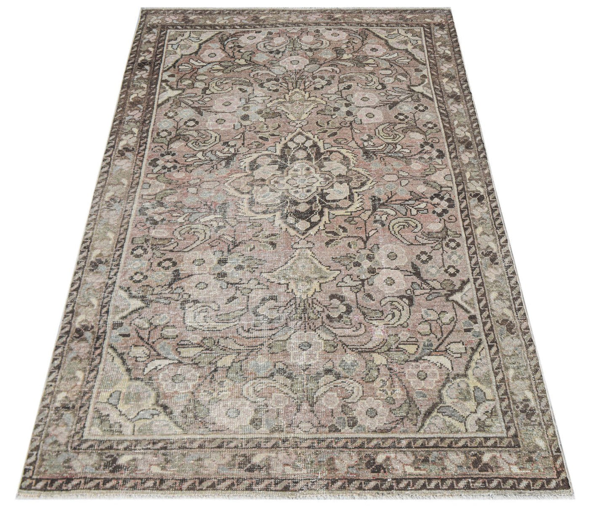 A vintage handwoven Persian rug featuring a faded floral pattern in muted pink and brown tones.