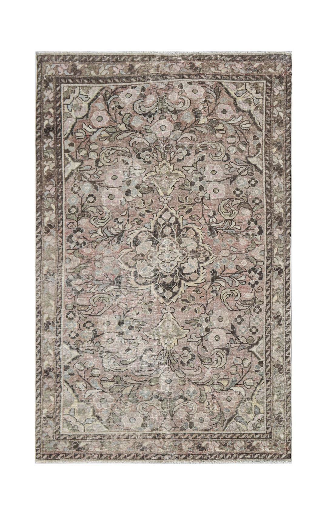Vintage Persian rug with a floral pattern in muted pinks and grays.