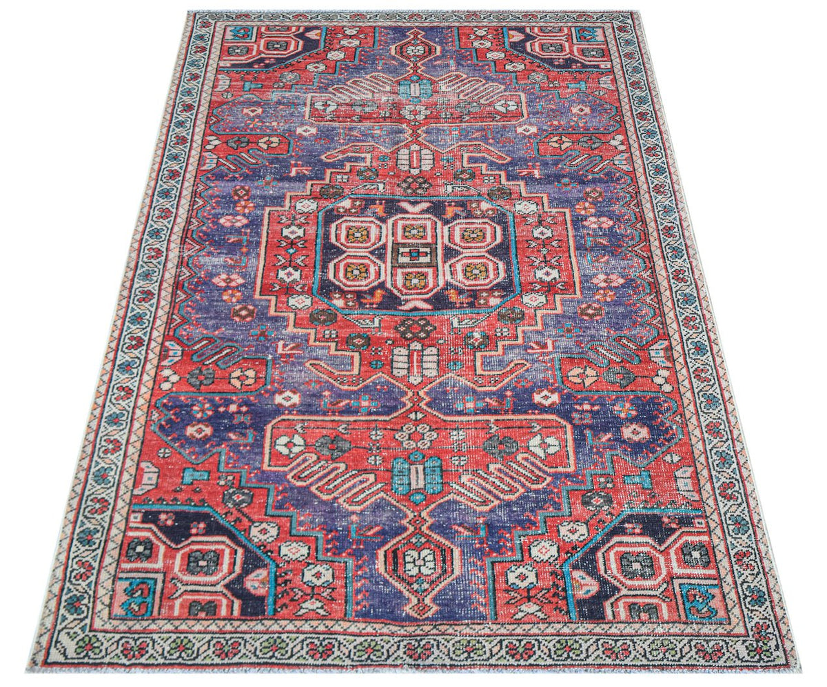 A handwoven vintage Persian rug featuring a geometric pattern in shades of red and blue.