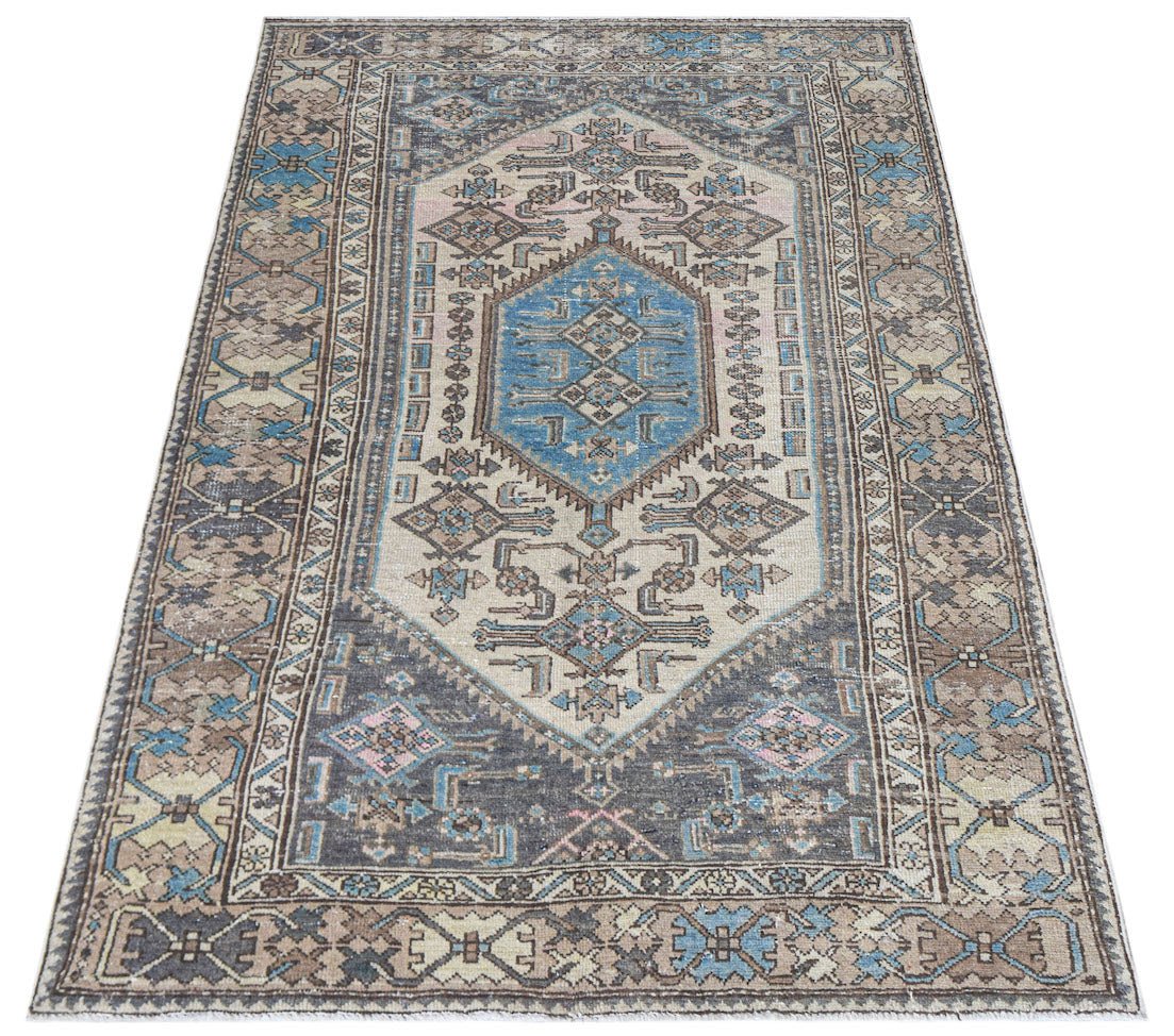 A handwoven vintage Persian rug featuring a central blue medallion on a beige and grey field.