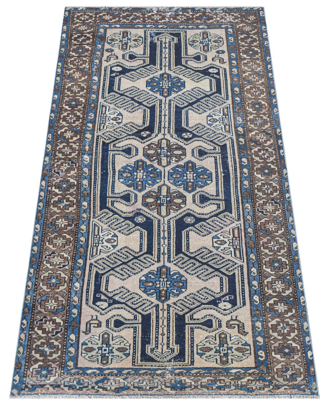 A handwoven vintage Persian rug featuring a geometric blue and brown pattern on a beige field.