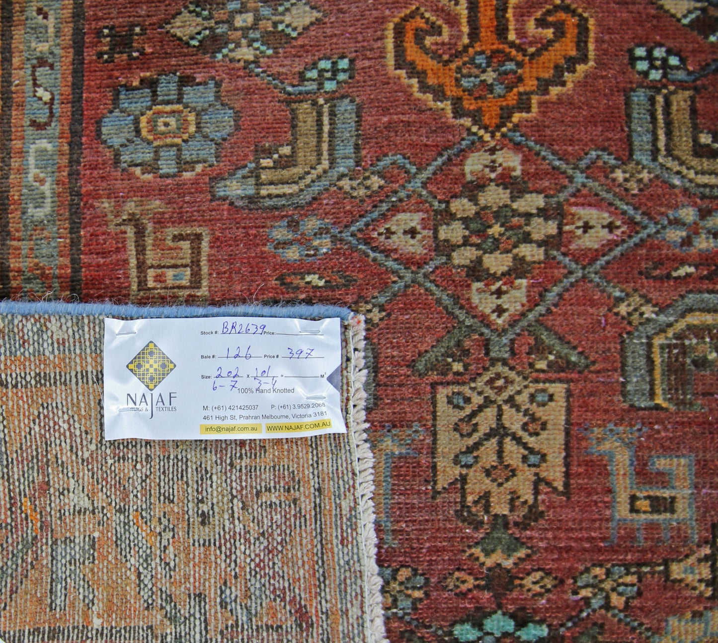 A vintage Persian rug with a geometric pattern in shades of red, blue, and tan.