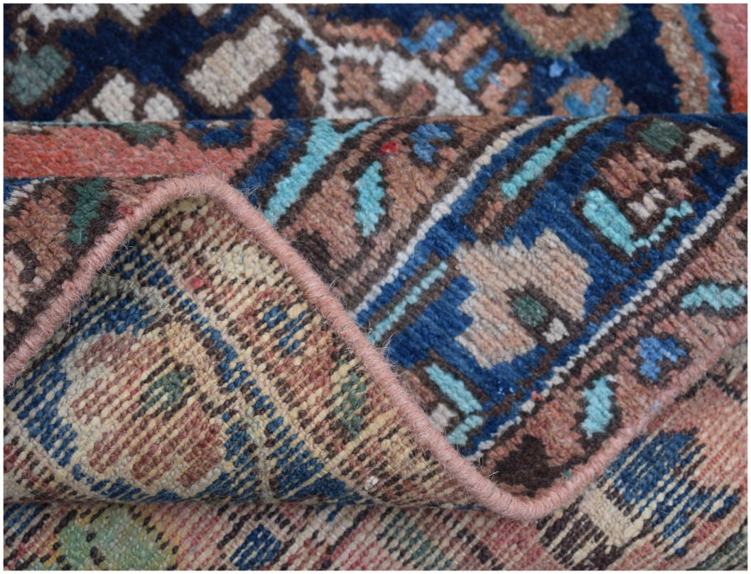 A close-up view of a handmade vintage Persian wool rug with a folded corner showing its texture.