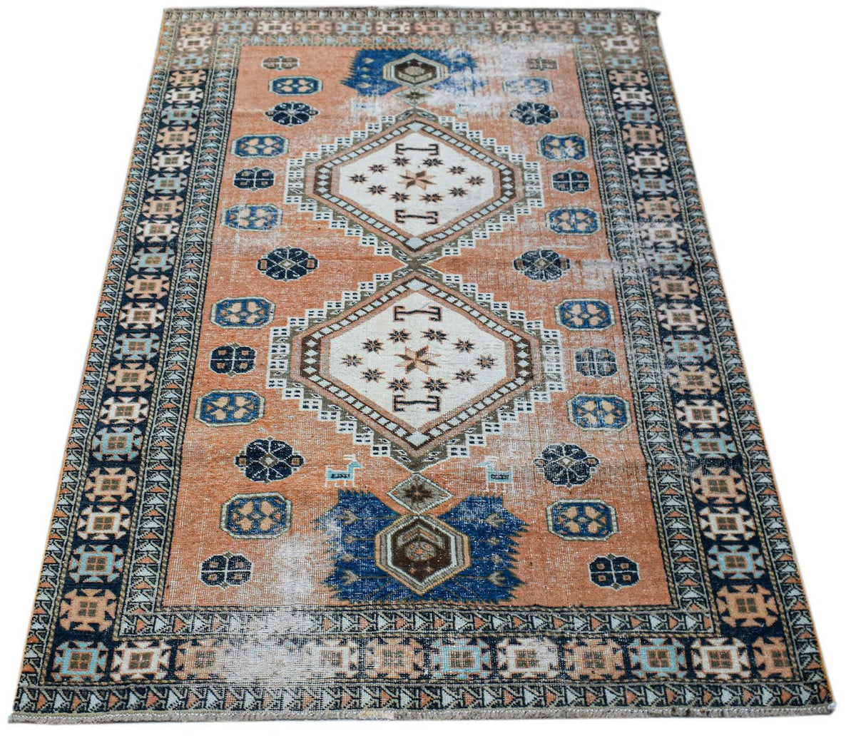A vintage handwoven Persian rug featuring a geometric diamond pattern in orange and blue tones.