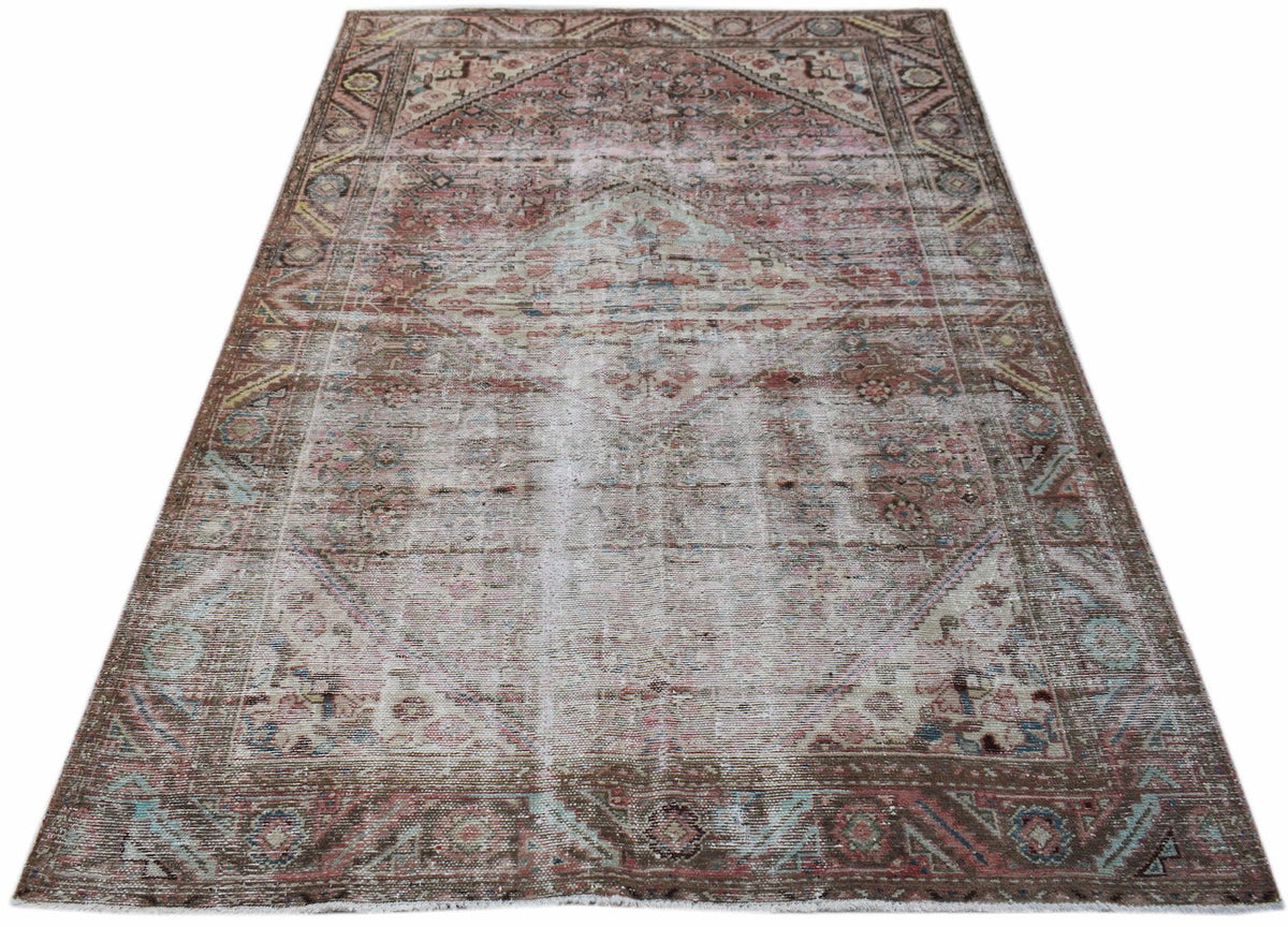 A handwoven vintage Persian rug featuring a faded geometric pattern in muted red and brown tones.