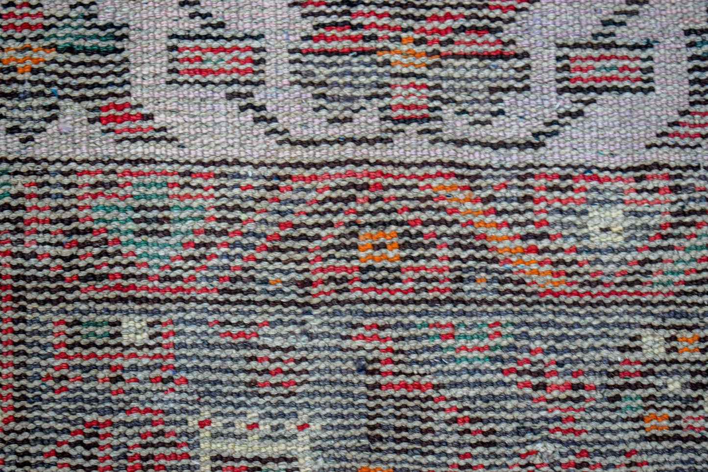 A close-up view of a handwoven vintage Persian rug featuring a textured pattern of colorful threads.