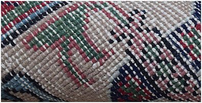 A close-up view of a handwoven vintage Persian rug featuring intricate geometric patterns in wool.