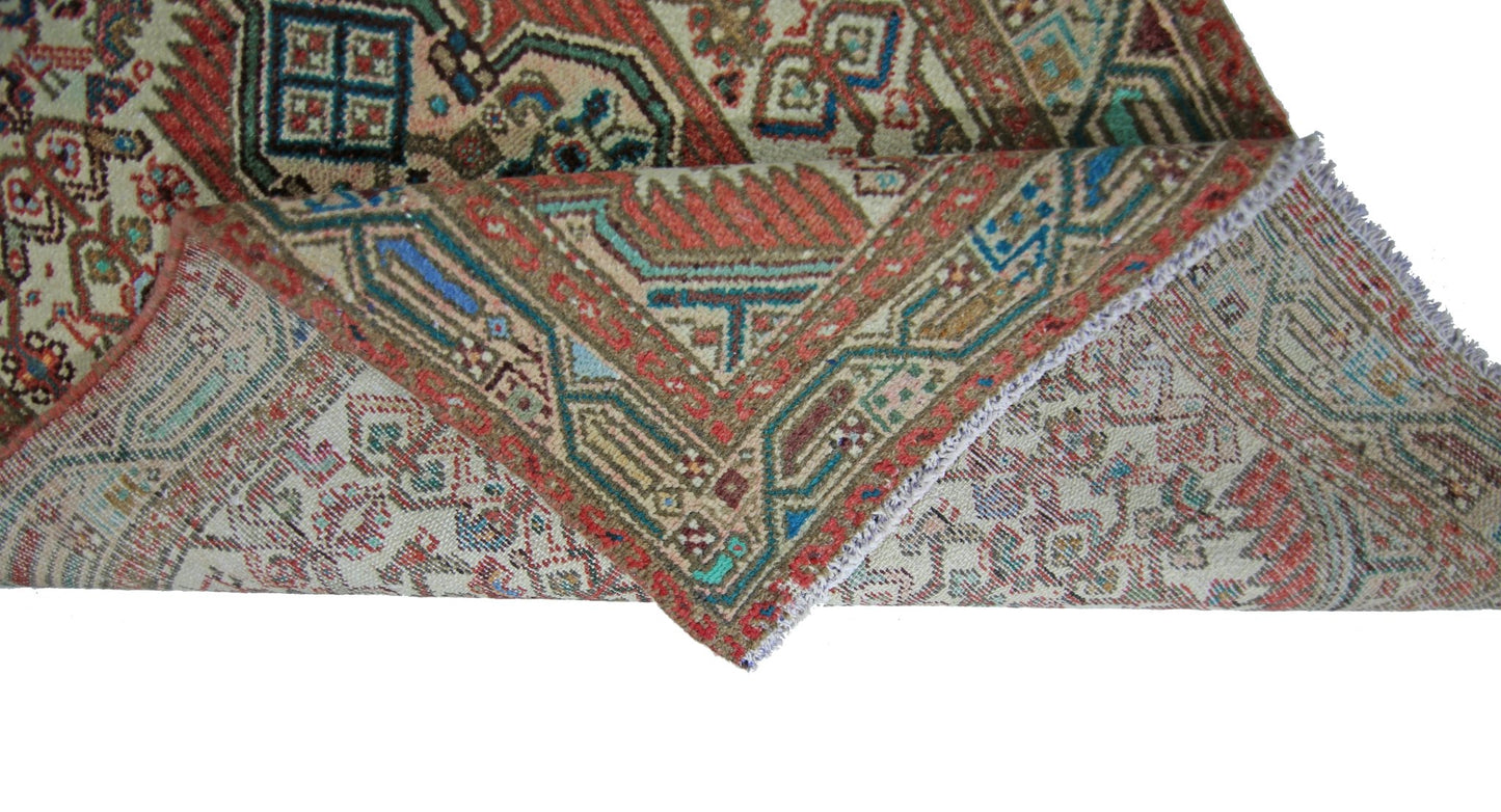 A vintage Persian runner with intricate geometric patterns in red, blue, and beige wool.