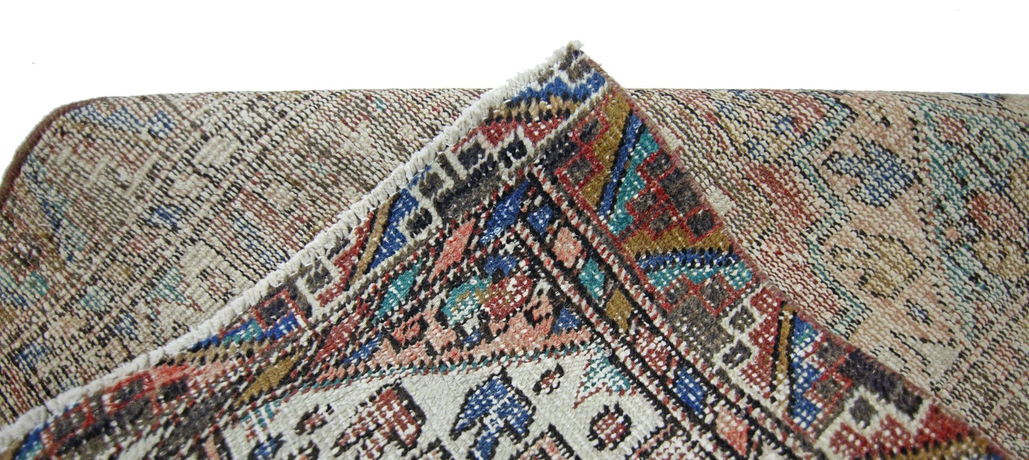 A corner of a vintage Persian runner showing intricate geometric patterns in wool on cotton.