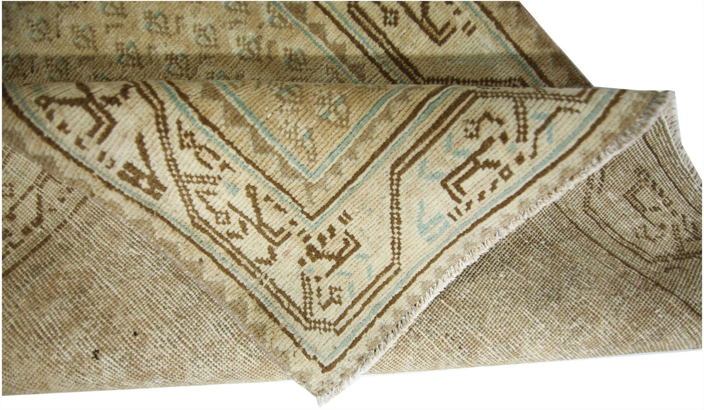 A folded vintage Persian runner featuring a geometric pattern in beige and light blue tones.
