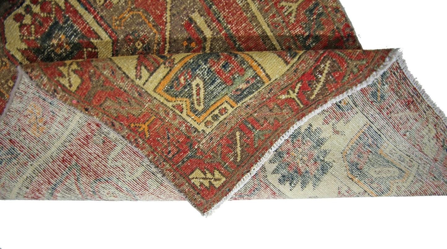 A corner of a vintage Persian runner with a folded edge showing its wool pile and cotton base.