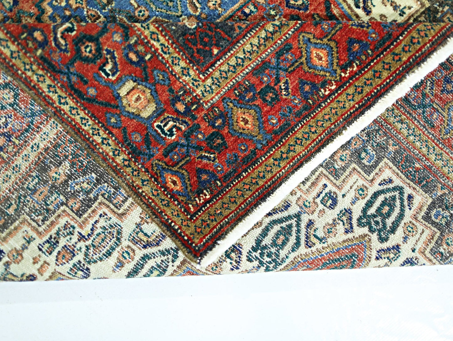 A vintage Persian Senneh rug with intricate geometric patterns in red, blue, and cream tones.