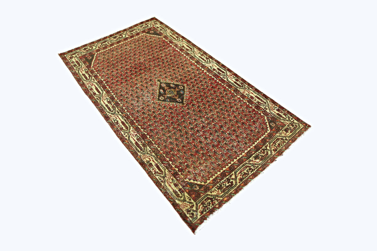 A vintage Persian Saraband rug featuring a red field with a repeating pattern and a central motif.