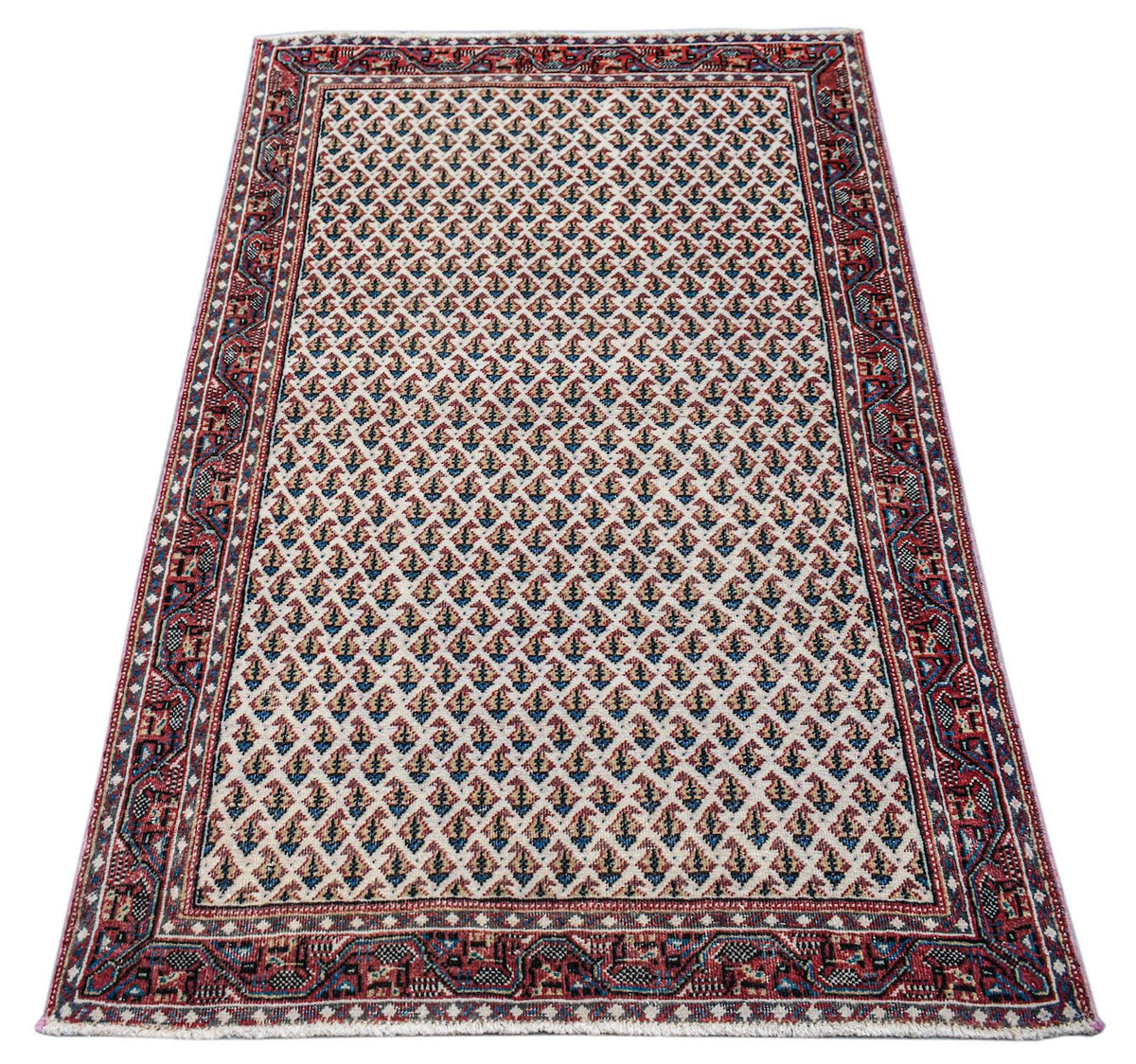 A vintage handwoven Persian Saraband rug featuring a repeating boteh pattern on a cream field.