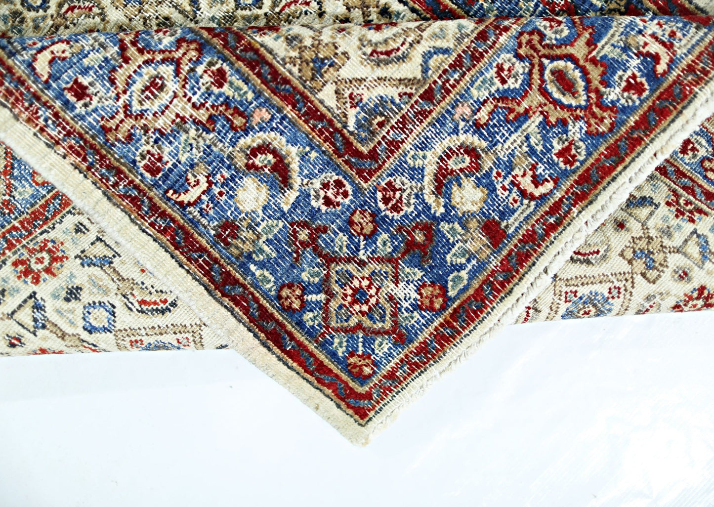 A vintage Persian Saraband rug featuring a blue border with intricate red and cream floral patterns.