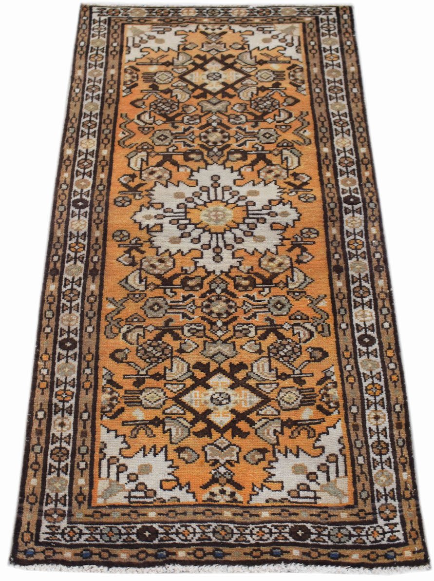 A handwoven vintage Persian runner rug featuring a geometric floral pattern in orange and brown.