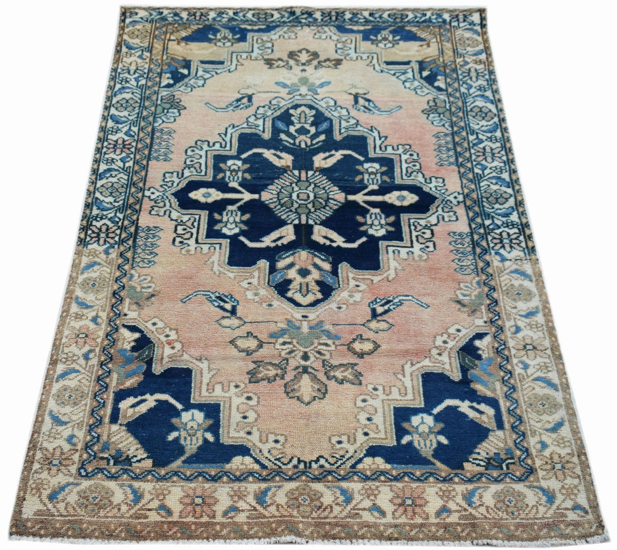 A vintage Persian Sarouk rug featuring a central blue medallion on a faded pink field.