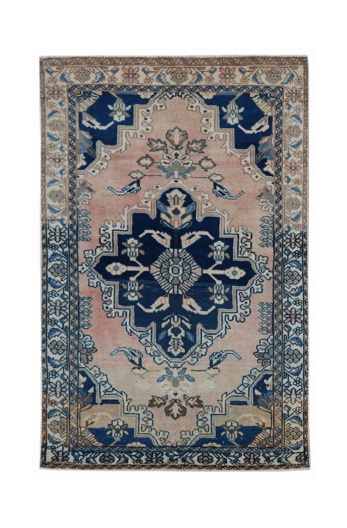 A vintage Persian Sarouk rug featuring a central blue medallion on a faded pink field.