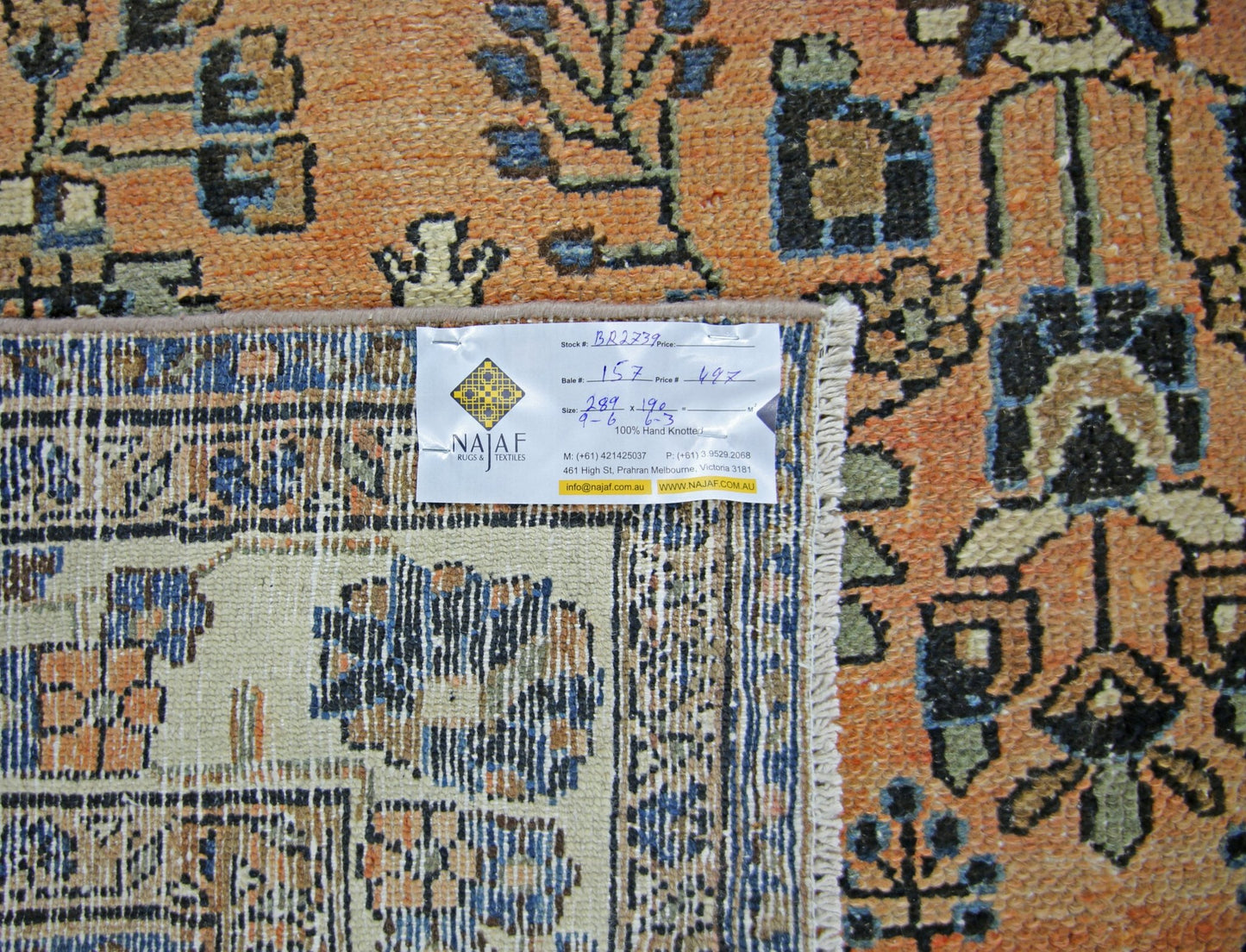 A vintage Persian Sarouk rug featuring a detailed floral pattern in orange, blue, and cream tones.