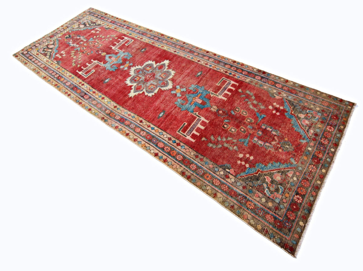 Vintage Persian Sarouk runner in red wool with intricate blue and cream floral patterns and a decorative border.