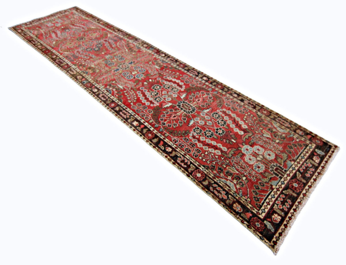 Vintage Persian Sarouk runner in red with intricate floral patterns, vines, and a dark decorative border.